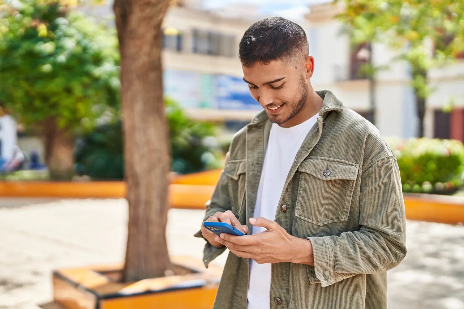 Junger Mann schaut fröhlich auf sein Smartphone.