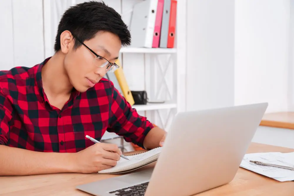 Junger Man mit Notizblock und Laptop in einer Test-Situation