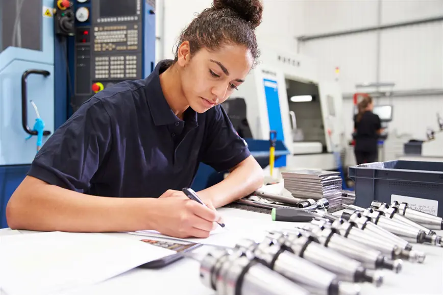 Junge Frau dokumentiert ihre technischen Arbeiten am Arbeitsplatz.