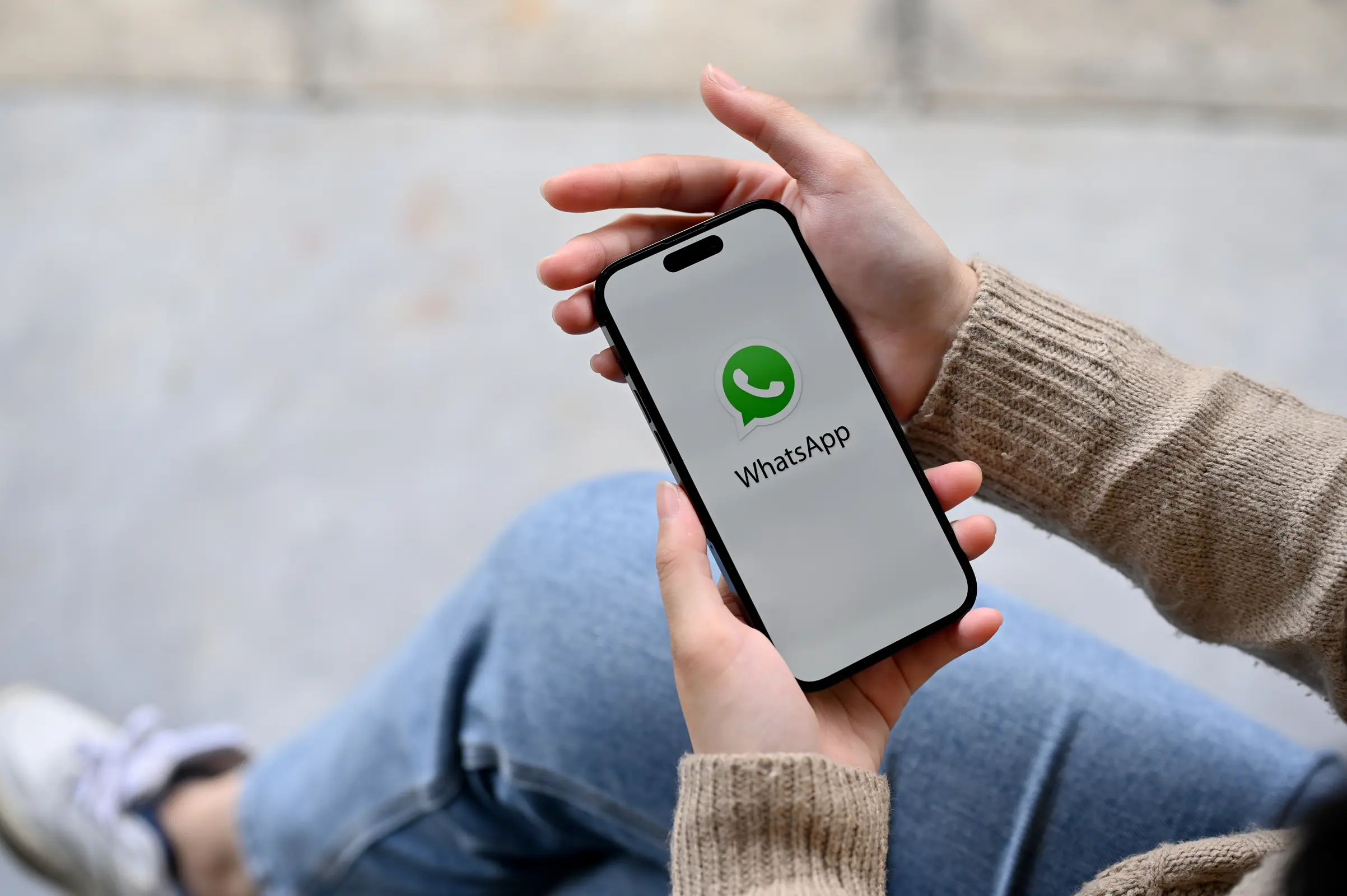 Jemand hat ein Smartphone in der Hand, auf dem WhatsApp geöffnet ist.