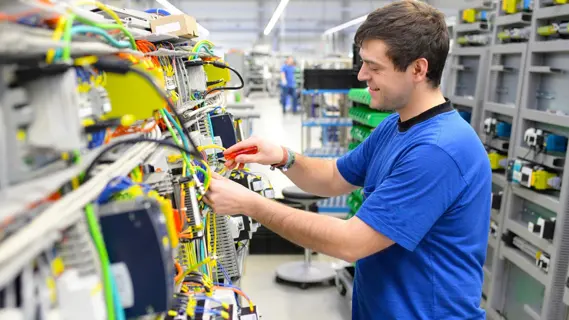 Beispielsweise die Ausbildung zur IndustrielektrikerIn dauert nur 2 Jahre - im Bild: Junger Mann montiert elektronische Bauteile in einer Fabrik.