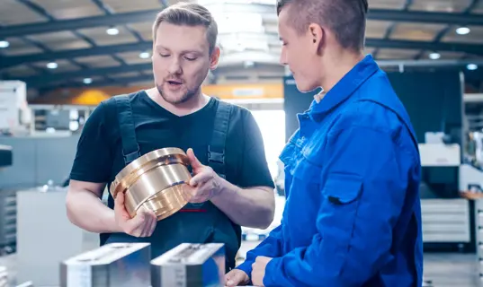 In der Ausbildung gilt nicht der Mindestlohn, sondern die Ausbildungsvergütung; da gibt es große Unterschiede - im Bild: Ausbilder und Azubi in der Werkhalle im Gespräch.