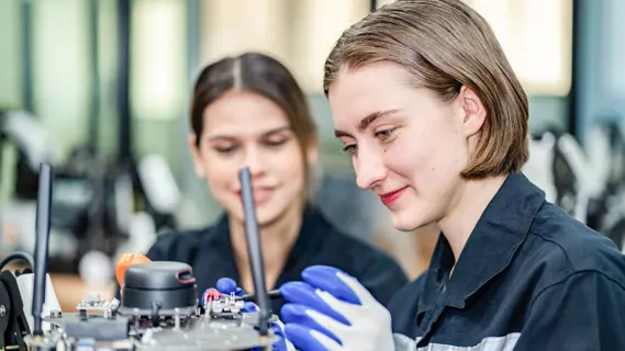 Ein Ausbildungsplan ist an die Bedingungen im Betrieb angepasst - im Bild: zwei weibliche Azubis bei technischen Arbeiten in der Fabrik.