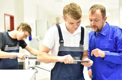 Ausbilder mit zwei Praktikanten in einem Metallbetrieb