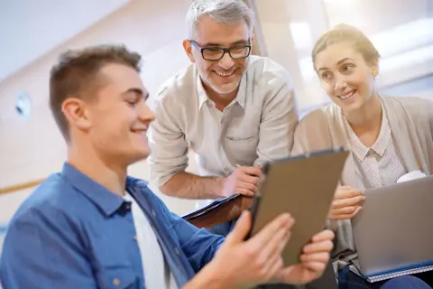 Schüler und Schülerin mit ihrem Vater bei der Berufsorientierung per Laptop-Recherche.