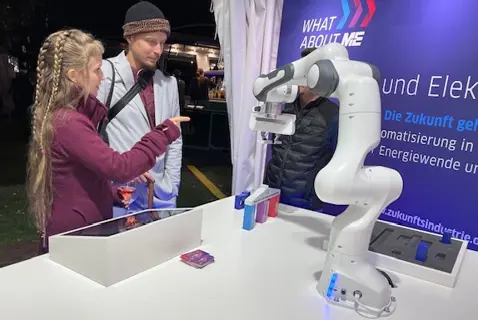 Cobot errichtet zusammen mit Schülerin ein kleines Gebäude.