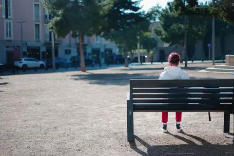Junge Frau sitzt auf einer Bank